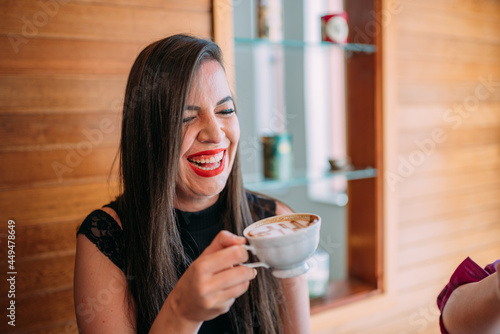 Young beautiful happy Latin woman enjoying cappuccino in a street cafe photo