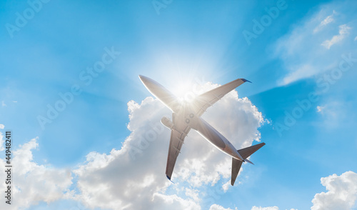 White passenger airplane under the clouds with sun rays - Travel by air transport