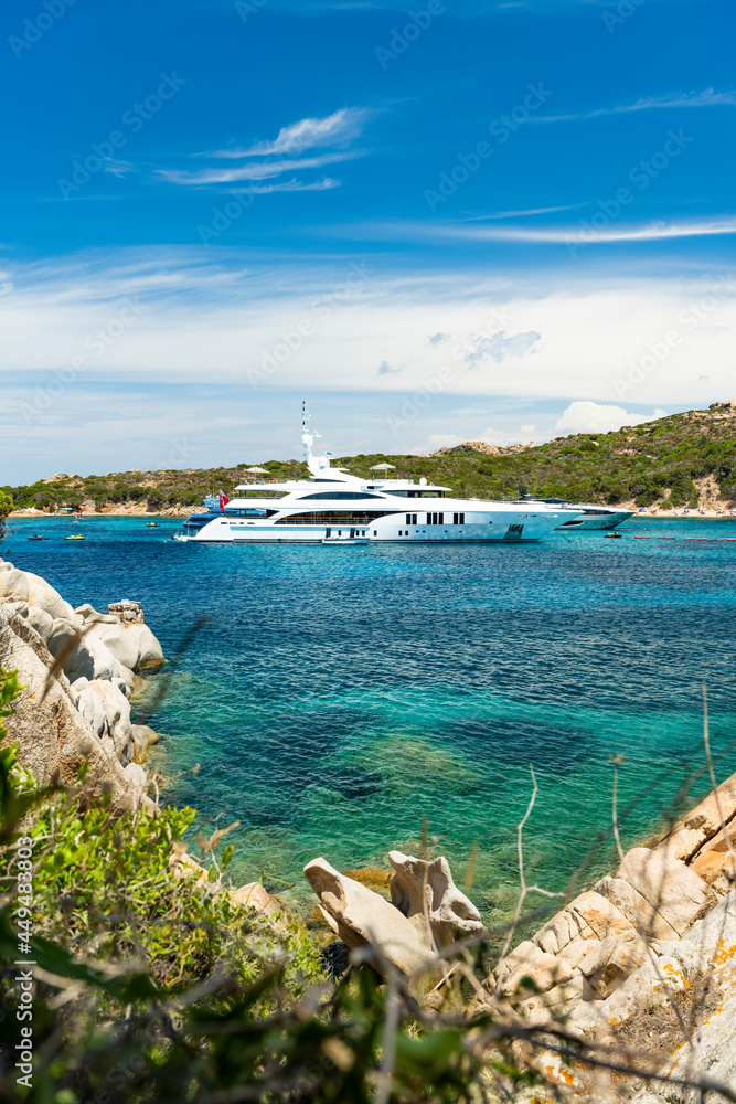 Stunning view of a bay of water with luxury yachts sailing on a turquoise water during a sunny day. La Maddalena archipelago, Sardinia, Italy.