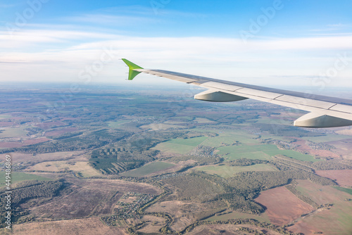 View of airplane wing, blue skies and the land during landing in Moscow, Russia. Airplane window view.