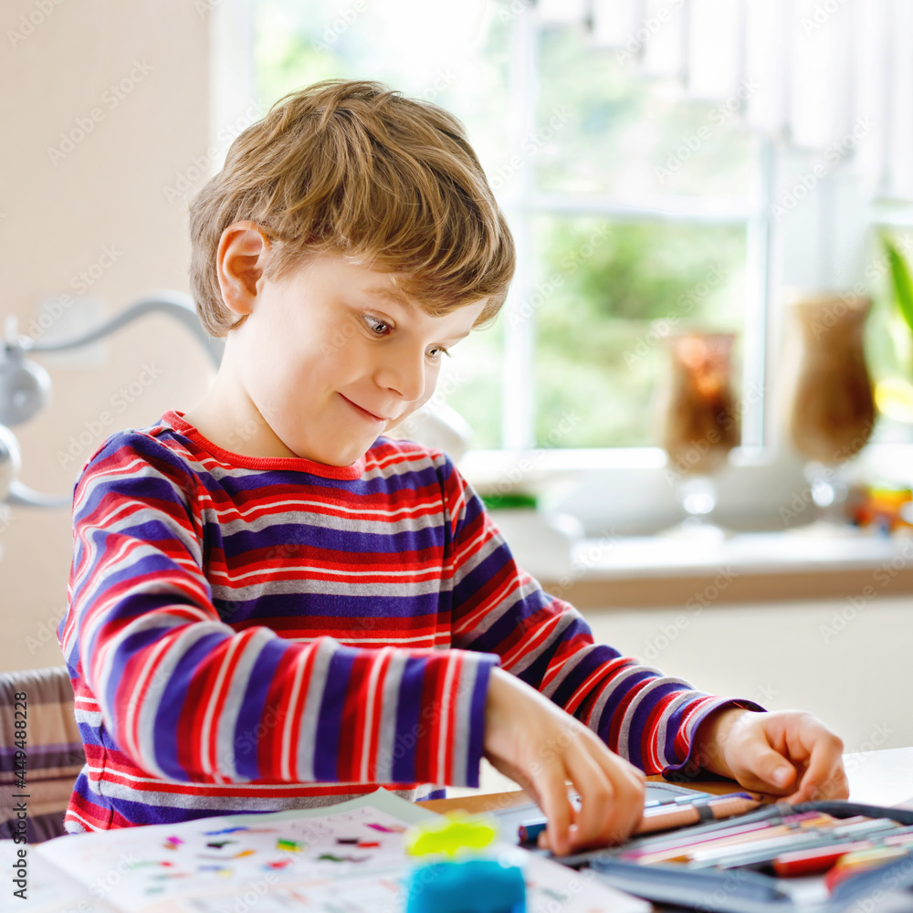 Happy smiling little kid boy at home making homework at the morning before the school starts. Little child doing excercise, indoors. Elementary school and education: Boy drawing geometric figures Happy smiling little kid boy at home making homework at the morning before the school starts. Little child doing excercise, indoors. Elementary school and education: Boy drawing geometric figures