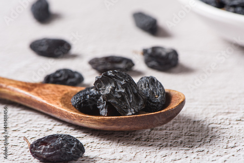 Dried fruits, pile of black raisins on table.