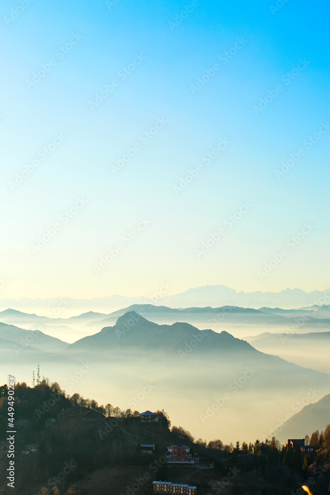 Under the blue sky, mountains are covered in clouds and fog