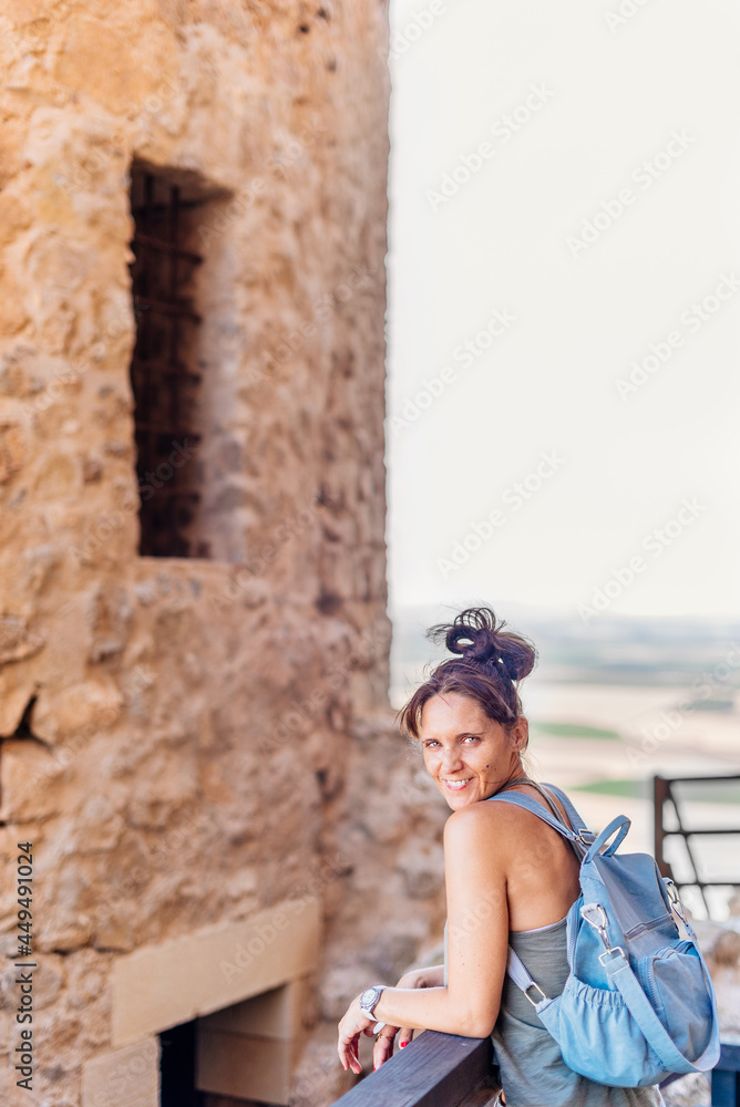 Woman leaning on a railing next to historic castle