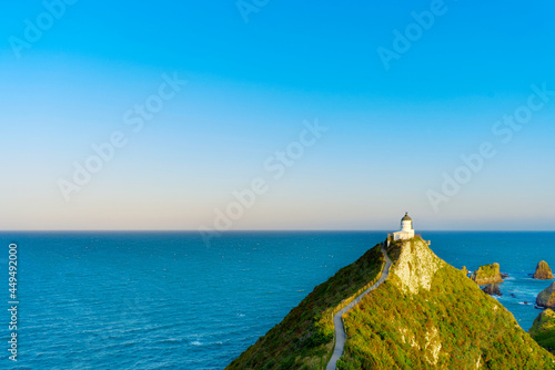 A long shot of a lighthouse at Nugget Point in Otago, South Island, New Zealand under blue sky photo