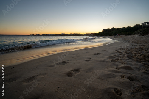 View of lapping waves on sand at sunset
