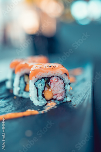 Close up shot of a spicy salmon sushi roll on a black stone tray. Selective focus on sushi filling, blurred background. Japanese style food. photo