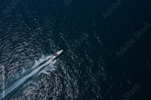 Large boat on the water in motion top view. Travel on high-speed boats on the water. Luxury motor boat on dark blue water aerial view. Speedboat is fast moving in dark water.