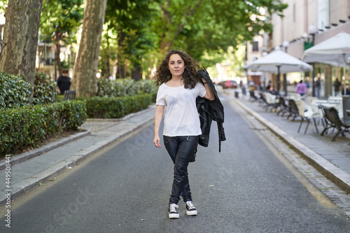 young woman dressed in black leather and white t-shirt in the middle of the road