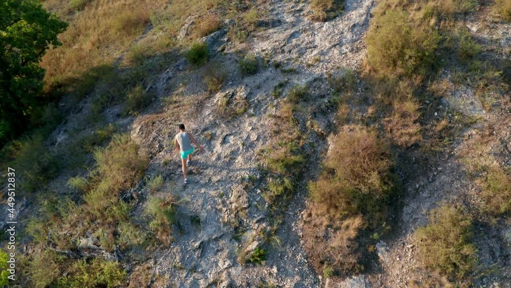 A young man in sportswear climbs the peak of the mountain. The concept of tourism, hiking in the mountains. The beautiful mountain slope is covered with rare yellow shrubs. High quality. 4k footage. A young man in sportswear climbs the peak of the mountain. The concept of tourism, hiking in the mountains. The beautiful mountain slope is covered with rare yellow shrubs. High quality. 4k footage.