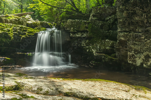 Rocks overgrown with moss. Waterfall in the forest. Summer.