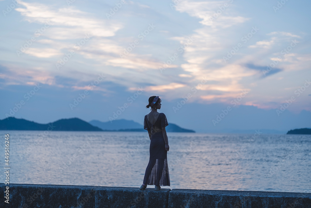 Fototapeta premium 夕暮れの海にいる女性