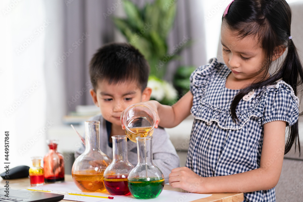 Asian 5 years old student and little brother looking to oil and water separation for liquid density science experimental at home , concept of homeschool, learn through play for kid in the family life. Asian 5 years old student and little brother looking to oil and water separation for liquid density science experimental at home , concept of homeschool, learn through play for kid in the family life.
