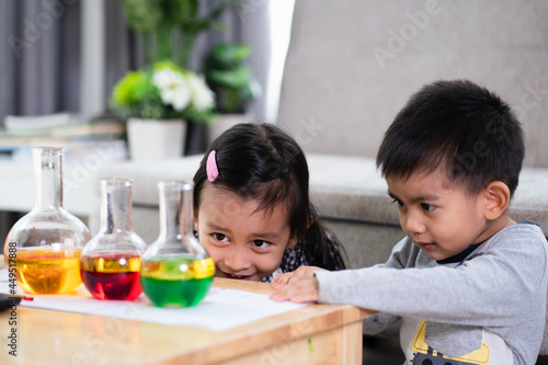 Asian 5 years old student and little brother looking to oil and water separation for liquid density science experimental at home , concept of homeschool, learn through play for kid in the family life.