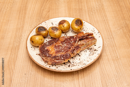 Super entrecote with sea salt and seasonal potatoes or cachelos on a white plate and wooden table photo