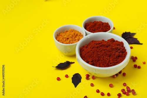 Aromatic spices in white bowls on yellow background