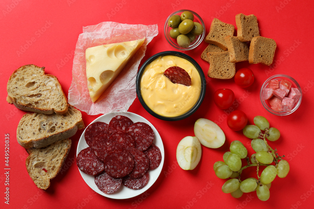 Concept of delicious food with fondue on red background Concept of delicious food with fondue on red background