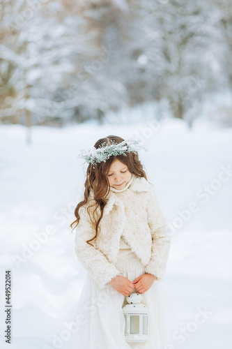 Adorable little girl holding Christmas lantern outdoors on beautiful winter snow day