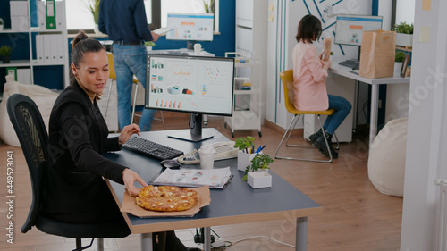 Photos Businesswoman on lunch break at her table eating pizza fastfood delivery