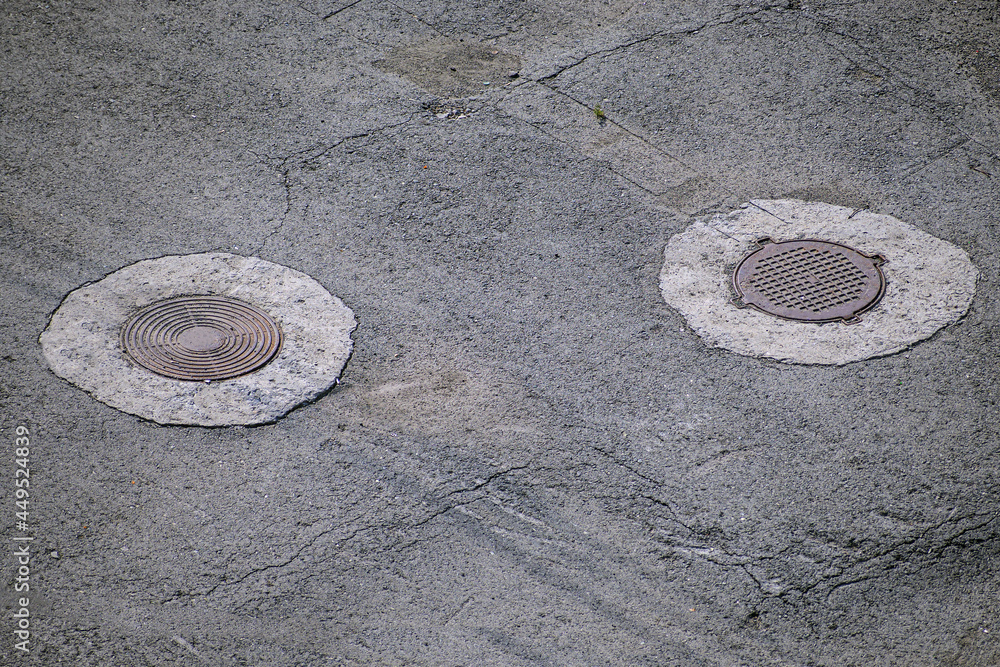 Hatches of underground utilities in the city sidewalk on a summer day