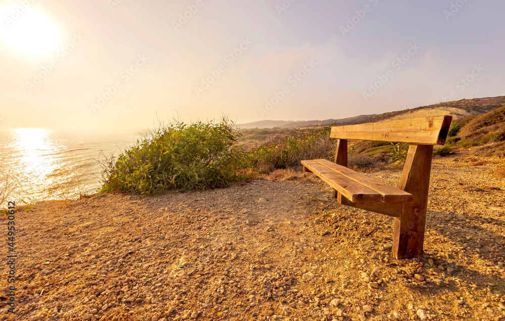 amazing scenic view at a sea shore from a mountain with nice bench on the foreground and blue sky and sea on the background , rest on a rock landscape