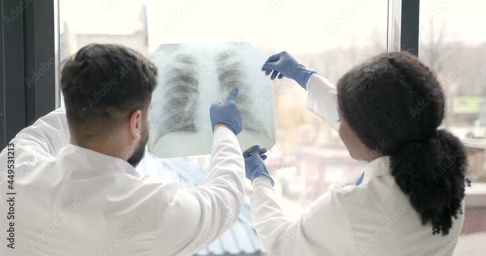 Doctor and coworker standing and looking at x-rays in clinic Doctor and coworker standing and looking at x-rays in clinic