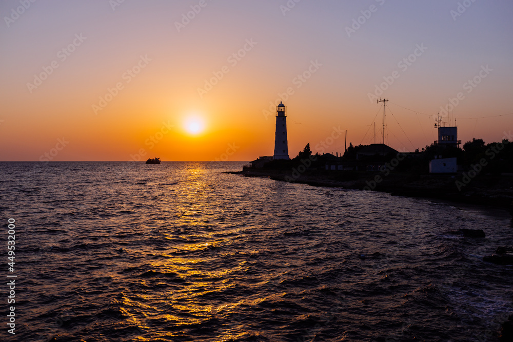 Lighthouse on the sea coast at sunset