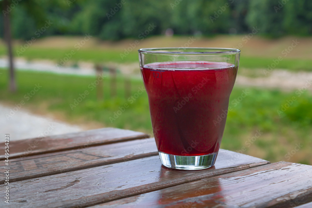 Close up of a glass of blueberry juice on a wooden table, nature background Close up of a glass of blueberry juice on a wooden table, nature background