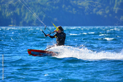 woman practicing extreme sport, kitesurfing at speed in the waters of a lake