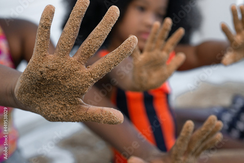 Close up hands, dark skinned kid show sand on hands after playing with sand on white background, selective focus