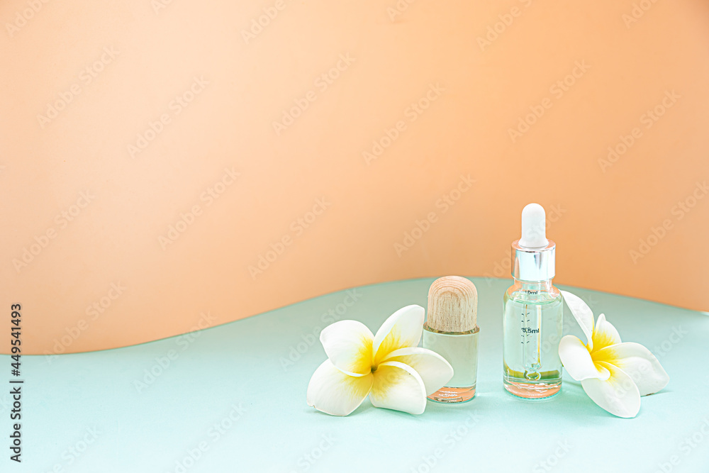 A bottle of essential oils and tropical flower on a white background. Skin and body care concept. A bottle of essential oils and tropical flower on a white background. Skin and body care concept.