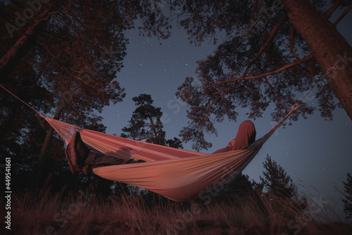Obraz na plátně A man sleeps in a hammock on a starry night. Campfire lighting