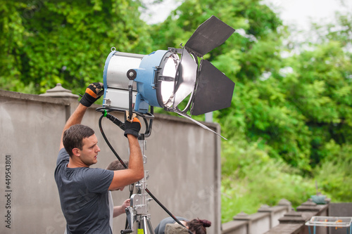 Behind the scene. Filmmaking lighting technician electric engineer adjusting and setup lights for movie film scene. Light Department. Film Crew