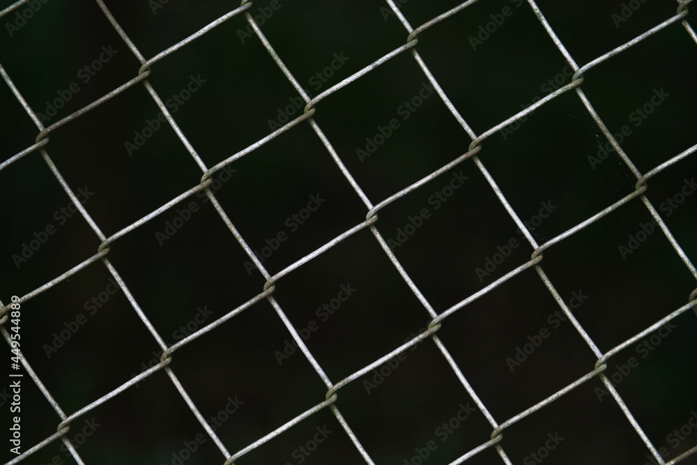 A wire mesh fence with dark background