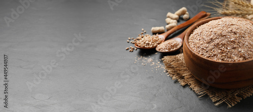 Wheat bran in bowl on black table. Space for text