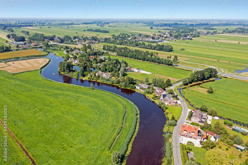 Aerial from a traditional dutch landscape: A little river, houses and flat land in the Netherlands