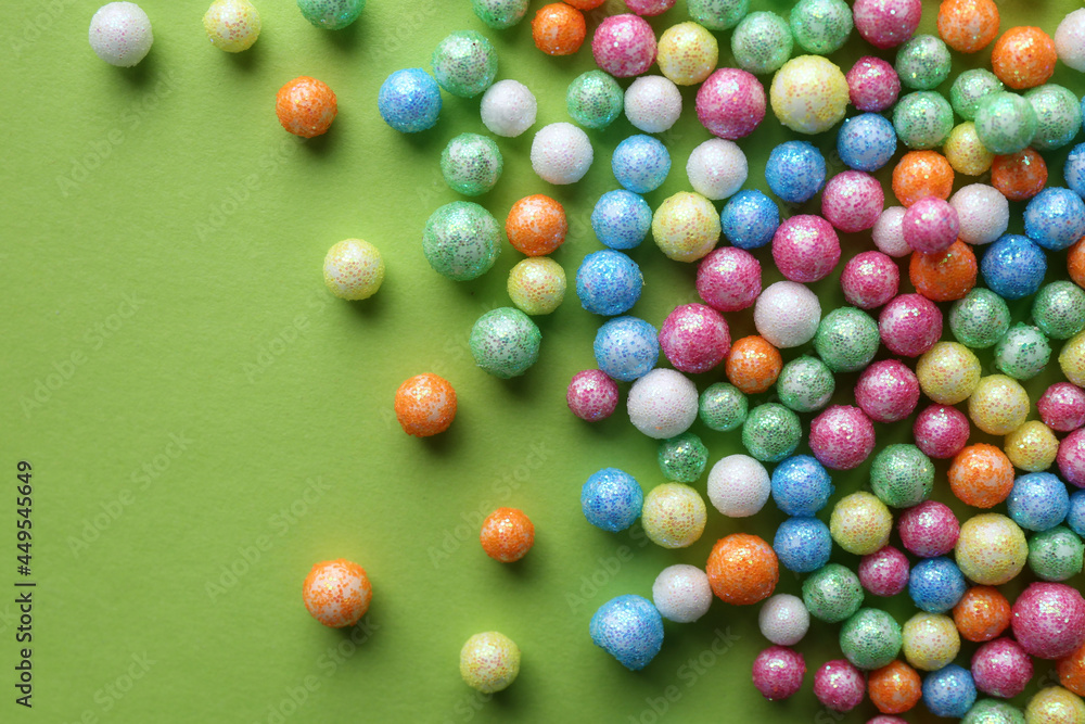 Small colorful beads on green background, flat lay Small colorful beads on green background, flat lay