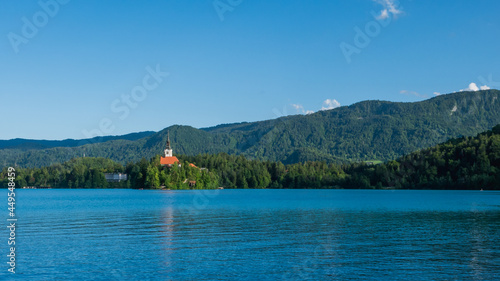 View of beautiful Lake Bled (Blejsko Jezero) with the Pilgrimage Church of the Assumption of Maria on a small island and Bled Castle and Julian Alps at backgroud at summer time.