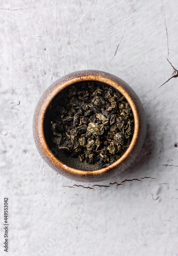 selective focus, natural green leaf tea. brewing in a clay bowl. vertical angle, macro. on a light background. for menus and cafes