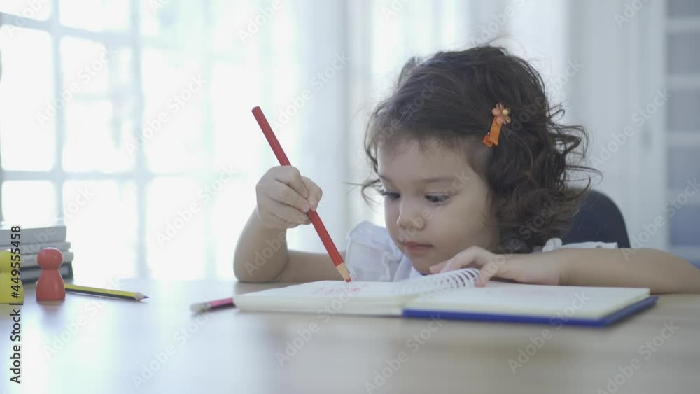 Little Girl Drawing on Paper with Colored Pencils. Children education. Little Girl Drawing on Paper with Colored Pencils. Children education.