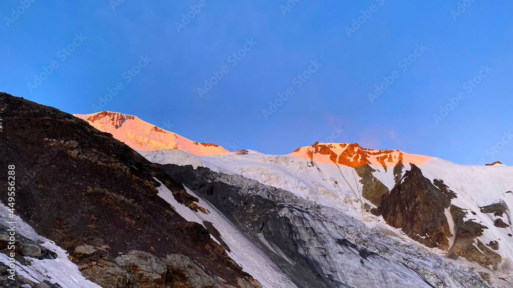 Dawn in the mountains. Majestic beautiful mountains, hills, cliffs and a glacier.