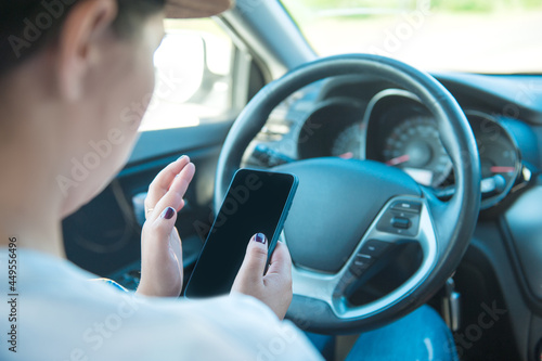 Woman with mobile phone in hands sitting inside car