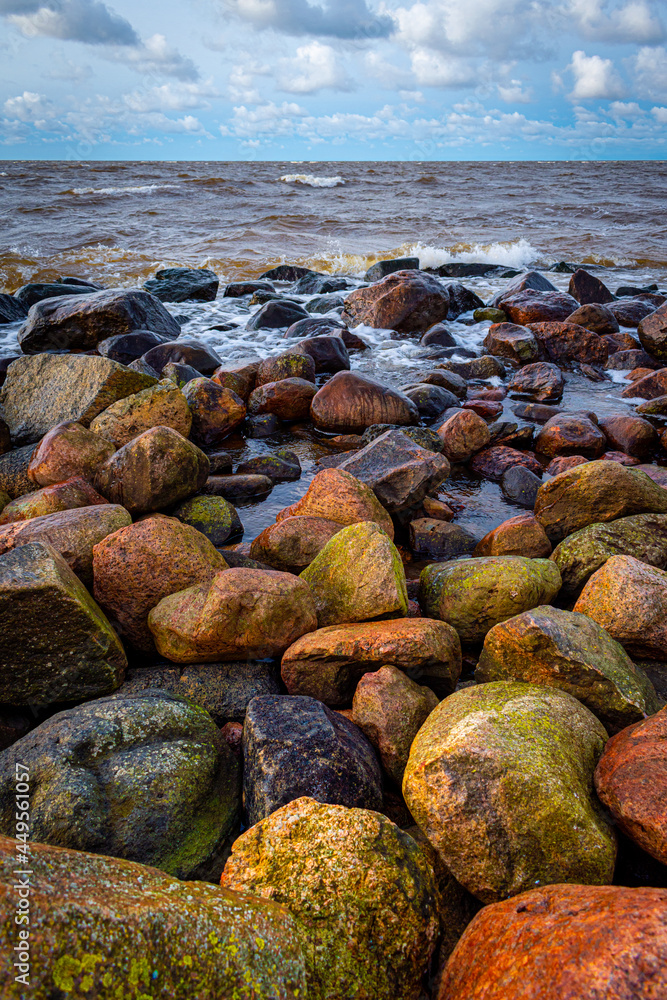 The rocky Ainazi pier dividing Latvia and Estonia by the Baltic Sea. Stone pier during windy day, colorful rocks and waves crashing on them.