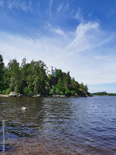 View from the shore of the Ludwigsburg Chapel on Ludwigstein Island in the Monrepos Rock Nature Park of Vyborg against a beautiful blue sky with clouds.