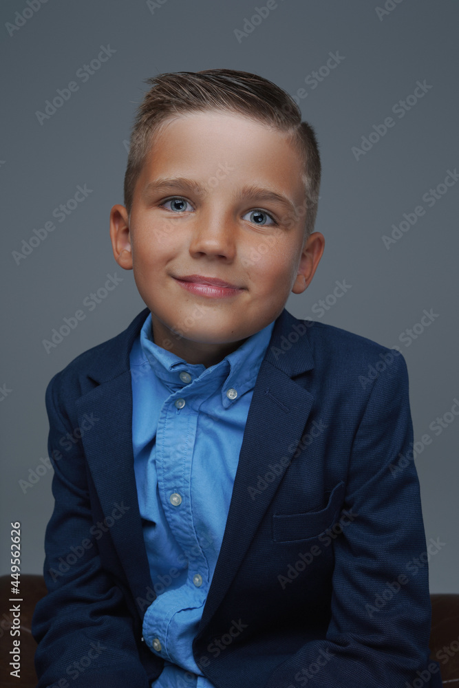 Joyful kid weared in suit posing against gray background Joyful kid weared in suit posing against gray background