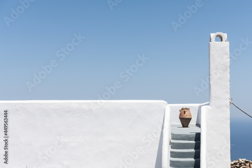 White stairs with a jar  of a buildings in Pyrgos Santorini, Greece with blue sky in a sunny warm day in July 2021.