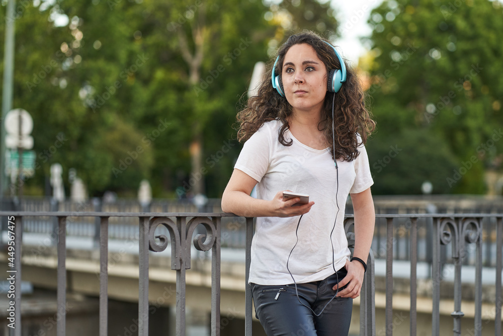 woman listens to music with her headphones connected to her smartphone