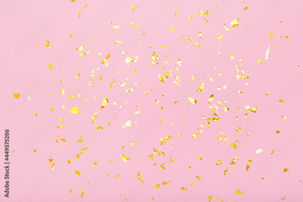 Golden glitter confetti sparkles on pastel pink background. Flat lay, top view. Holiday, festive, party backdrop.