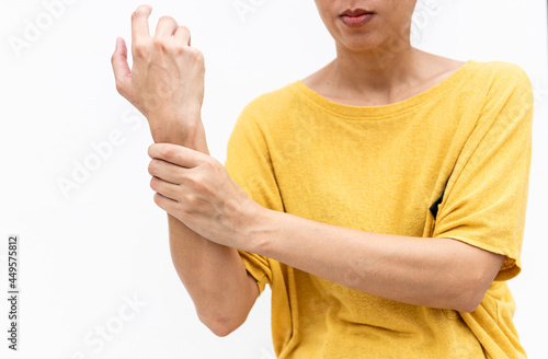 Woman in yellow clothes using hand to hold wrist with feeling pain, suffer, hurt and tingling. Concept of Guillain barre syndrome and numb hands disease. photo