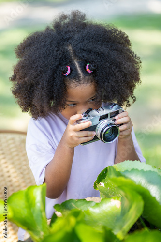 Fototapeta Cute afro curly girl A girl with a camera I am shooting the lotus flower